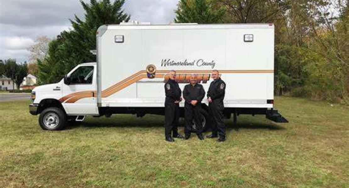 Uniformed investigators standing in front of investigation vehicle